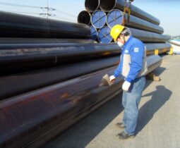 Worker inspecting stacked industrial pipes.